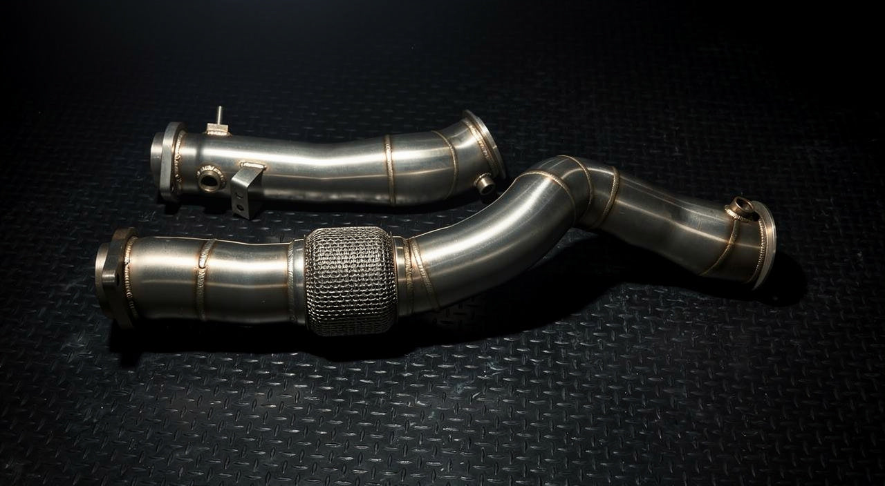 Bare stainless S58 downpipes with flex section, laid flat