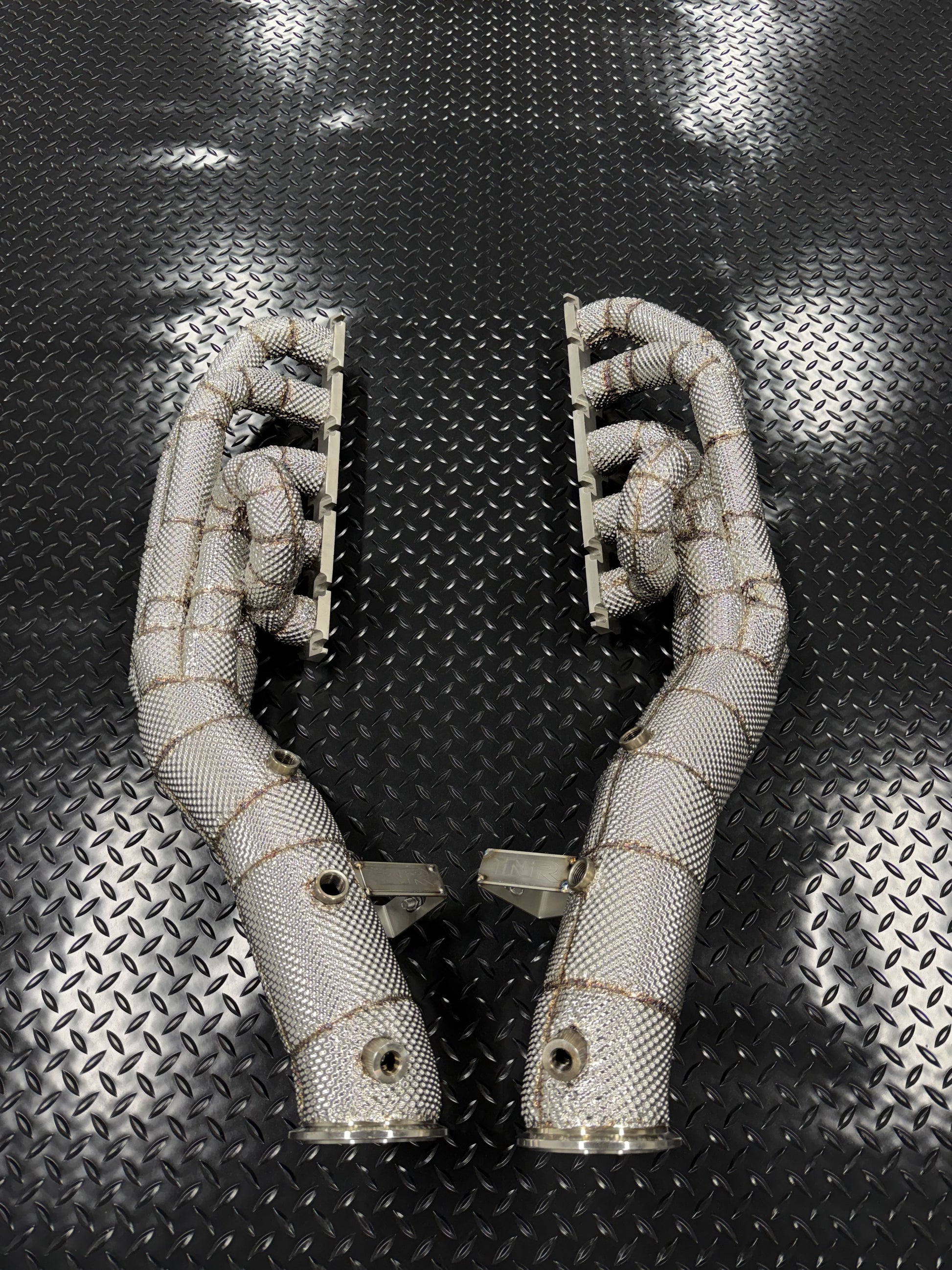 Pair of heat-wrapped V10 long-tube headers standing on diamond plate